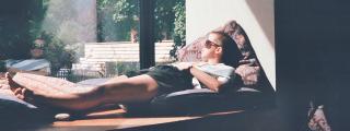 Banner zeigt Person, die vor Fenster in der Sonne liegt