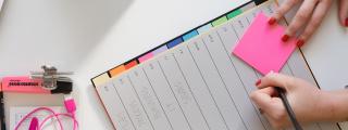 Banner zeigt Hände, die auf Post-it schreiben