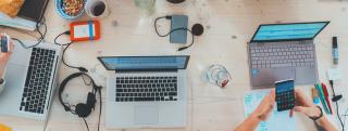 Banner zeigt Laptops, Kabel und andere Arbeitsmittel auf Schreibtisch
